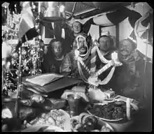 Roald Amundsen y su tripulación en el Gjøa, celebrando la Navidad en Gjoa Haven (Nunavut, Canadá) en 1903 durante su viaje por el paso del Noroeste. Helmer Hanssen, Amundsen, Lindstrøm, Gustav Wiik y Anton Lund están sentados a la mesa, y Peder Ristvedt está de pie detrás de ellos.