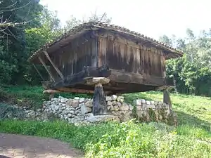 Cuerpo cúbico, cubierta de teja, tablas verticales llamadas cureñes; se ve el cruce en ángulo recto de las trabes