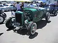 Roadster Hi-boy Deuce con motor de culata plana (con cabezal y escape de fábrica, pero alternador de encendido y admisión de doble carburador del mercado de accesorios), eje de tubo abatible y frenos de tambor