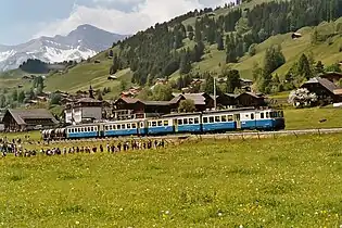 Coche bimotor eléctrico de vía métrica ABDe 8/8 4004 del MOB en Suiza, tirando de dos coches y de dos vagones de cemento