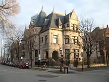 Casa de tres plantas. Los coches se alinean en la calle y los árboles no tienen hojas al ser invierno.