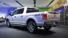 Vista posterior de una camioneta Ford F-150 del 2015, de color blanco y ruedas con llantas plateadas.