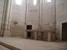 Presbiterio con un altar de piedra. A derecha e izquierda se ven las dos puertas por las que se entra a la chirola o sacristía.