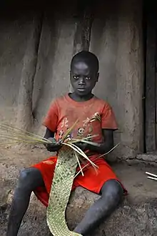 Niño aari tejiendo cestos.