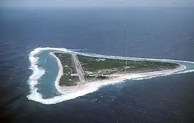 An airstrip and a red and white antenna mast on a small, green, triangular island