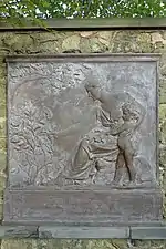 Bronze tablet of a woman handing a plant to a young boy