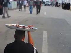 Un hombre con un plato lleno de dátiles, esperando a que los peregrinos de Arbain pasen a por ellos.