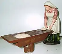 Panadera haciendo la masa en una artesa. Figurita del belén.