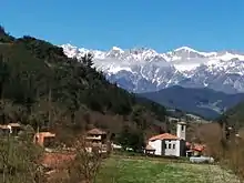 Vista de Cabezón de Liébana. La iglesia parroquial en primer término. Al fondo, los Picos de Europa.