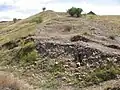 La muralla de la parte inferior del castro, donde se encontró una gran cantidad de puntas de flecha y de proyectiles metálicos pesados, de donde se deduce que esta fue la zona por donde se acometió el ataque más virulento a la muralla. Las hiladas detrás del derrumbe que están ordenadas, son las que delimitan el grosor de la muralla, alcanzando esta en torno a los 5 m de ancho.