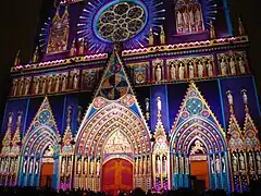 Photographie couleur de la façade vue de nuit et sur laquelle une image multicolore est projetée.