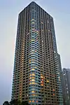 Ground-level view of a orange and white, rectangular, window-dotted high-rise