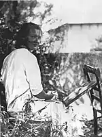 Fotografía en que Charlotte Salomon pintando el jardín se vuelve a la cámara