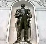 Bronze statue of a man standing with his hand on his sword at his hip