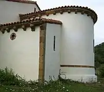 Ábside decorado con una cenefa tallada en piedra y canecillos bajo los aleros