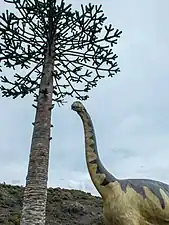 Modelo de un saurópodo y araucaria.