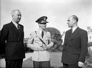 Un adolescent en uniforme, entouré de deux hommes de quarante-cinquante ans.