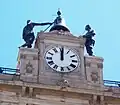 Detalle del reloj y estatuas.