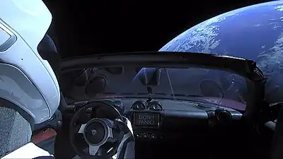 Vista de la cabina del coche, se aprecia la frase Don't Panic, referencia a la Guía del autoestopista galáctico