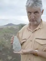 Enrique Baquedano en Olduvai con un bifaz de tipo amigdaloide en la Garganta de Olduvai. Tanzania, junio de 2012.