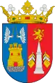 Escudo partido. 1º, de azur (azul), un castillo, de oro, mazonado de sable y aclarado de gules, sobre peñas de su color, surmontado de dos manos aladas, de plata, con una espada de oro, enfrentadas. 2º, de gules (rojo), un obelisco, de plata, acolado de seis banderas y sumado de un leon, de oro, armado de una espada y coronado. Al timbre, corona de marqués, conmemorando al título del Marqués de Villena.