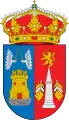 Escudo partido: 1º, de azur (azul), un Castillo, de oro, mazonado de sable y aclarado de gules, sobre peñas de su color, surmontado de dos manos aladas, de plata, con una espada de oro, enfrentadas. 2º, de gules (rojo), un obelisco, de plata, acolado de seis banderas y sumado de un leon, de oro, armado de una espada y coronado. Al timbre, corona real cerrada.