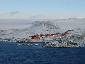 Vista de las rocas en la caleta Choza (a la izquierda de la punta Foca), junto con la Base Esperanza y la Estación R. Elichiribehety.