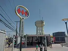 Letrero de acceso a la estación junto a la copa de agua.