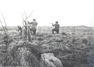 Mercenarios de Julius Popper disparando mientras en el suelo está el cadáver de un selknam.