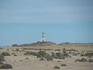 Vista desde lejos del Faro de Punta Medanosa. En primer plano se ve la pingüinera.