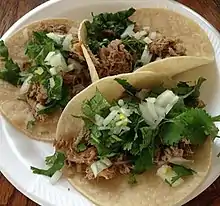 Gallos en tortilla de carne mechada con cebolla y culantro.