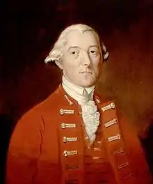 A half-height portrait of Carleton.  He wears a red coat with vest, over a white shirt with ruffles.  His white hair is drawn back, and he faces front with a neutral expression.