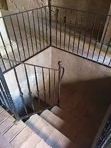 Escaleras que bajan a la gloria del Monasterio de Piedra. Son de ladrillo, y las rodea una barandilla de hierro forjado negro.