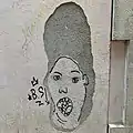 Grafiti en la pared de una calle de Mataró, aprovechando el desconchado para representar el cabello de Marge Simpson, 2021