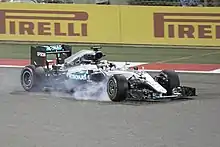 A Formula One car with smoke coming from the front right tire after a brake lockup