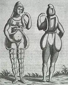 Una ilustración renacentista de frente y de espalda de un hermafrodita, mostrando a una persona con características faciales femeninas, pechos y lo que parece ser un pequeño penis o gran clítoris. Lleva una pequeña capucha y una toga atada en varios puntos alrededor de las piernas, que se abre por el frente. La apariencia por la parte trasera es de una concha de algún tipo, en la que faltan dos rectángulos en la cabeza y el torso. No tiene glúteos.