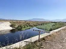 Letrero en humedal. Se ve el agua de fondo un poco del sitio.