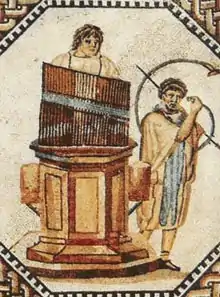 Mosaico del hydraulis, un órgano hidráulico, el primer instrumento de teclado en la historia, precursor de los instrumentos de pulsación. Inventado en el siglo III a. C. por Ctesibio de Alejandría.