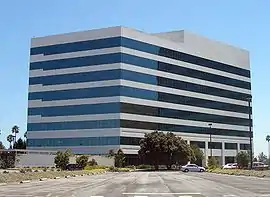 Nondescript eight-story beige building with black windows striped across