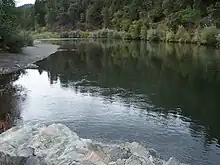 A wide placid river flows through the woods.