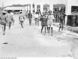 Indígenas portando rifles japoneses caminando por una calle en Brunéi al regresar a sus aldeas el 17 de junio de 1945.