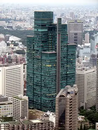 Ariel-view of a green, glass high-rise composed of square sections that rise to differing heights