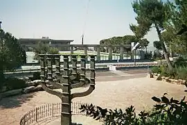 La menorá de la Knéset, realizada por el escultor judeoalemán Benno Elkan, ubicada en el Jardín de las Rosas, delante del edificio del parlamento israelí.