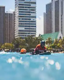 Jesse Billauer, a para surfing prone 2 surfer, paddling out with assistance at the 2022 Hawaii Adaptive Surfing Championships