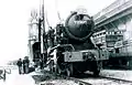 Una antigua locomotora de vapor del ejército británico llega a Hong Kong en 1947 para la sección británica del KCR. La Torre del Reloj está en el fondo.