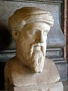 Marble bust of a man with a long, pointed beard, wearing a taenia, a kind of ancient Greek head covering in this case resembling a turban. The face is somewhat gaunt and has prominent, but thin, eyebrows, which seem halfway fixed into a scowl. The ends of his mustache are long a trail halfway down the length of his beard to about where the bottom of his chin would be if we could see it. None of the hair on his head is visible, since it is completely covered by the taenia.