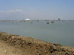Lago creado por lodo con flujo de lodo humeante de fondo.