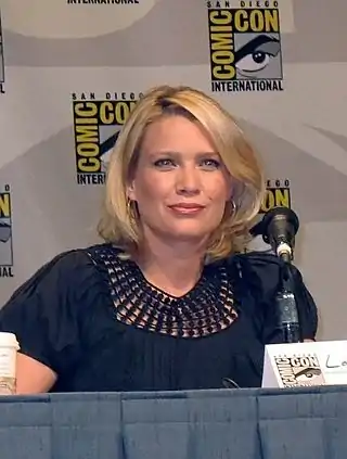 A woman with blonde hair sitting at a conference.