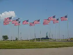 Banderas de Estados Unidos con la Estatua de la Libertad al fondo