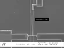  Una microfotografía de un voladizo vibrante. Los cursores en la imagen indican que la amplitud pico a pico de las vibraciones es de 17.57μm.